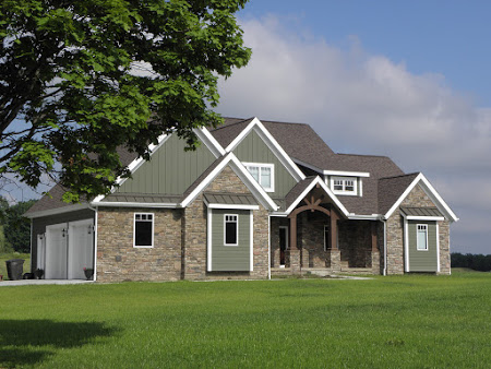 A large brick house with green grass and trees.