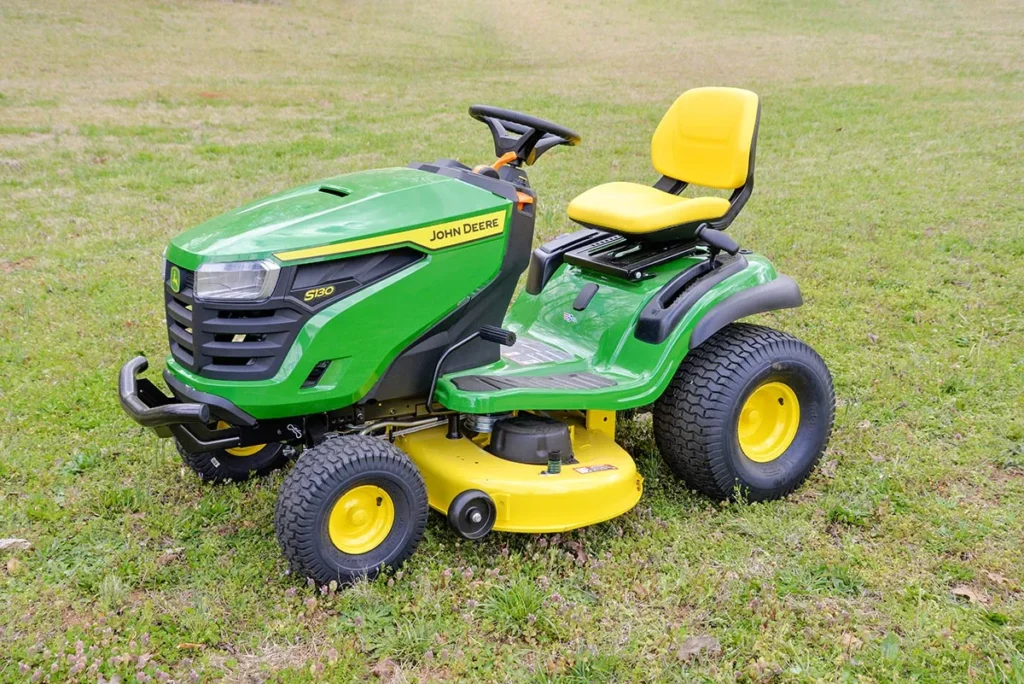 A green lawn mower sitting in the grass.