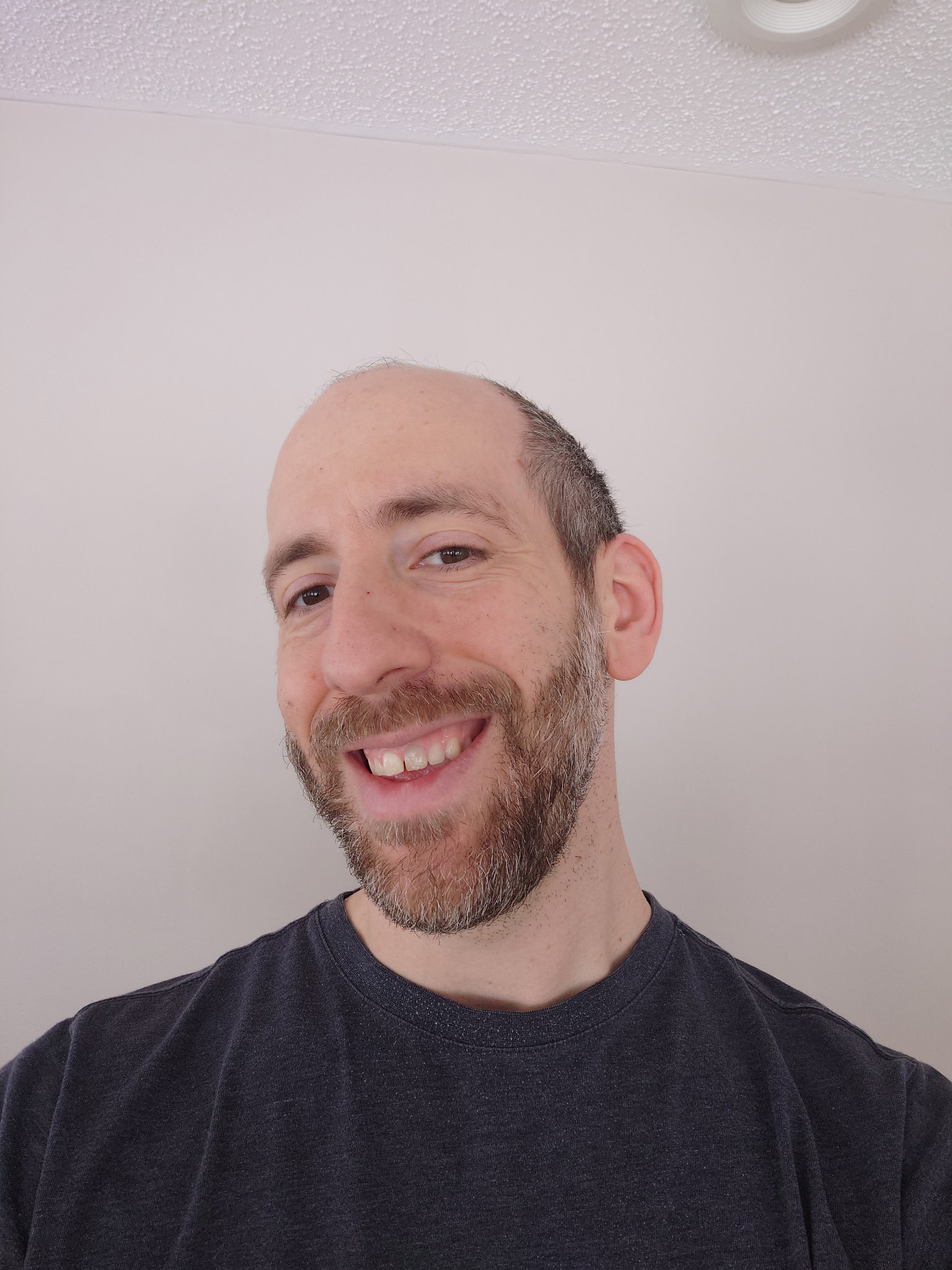 A man with a beard and mustache smiling for the camera.